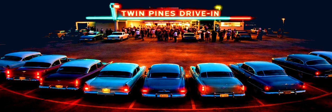 Classic 1950s cars gathered at Twin Pines Drive-In under glowing neon lights at dusk.